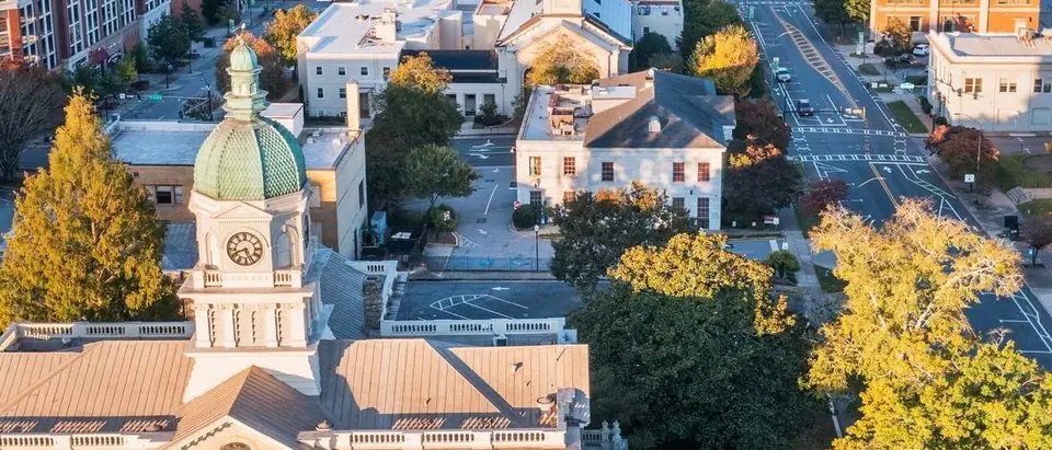Athens, Georgia from the air: the clock tower and green copper dome of City Hall above downtown streets and trees in early light