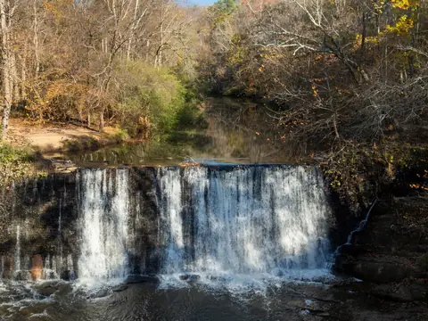 Water falling over the old stone mill dam on Vickery Creek in Roswell, Georgia, with autumn trees along both banks