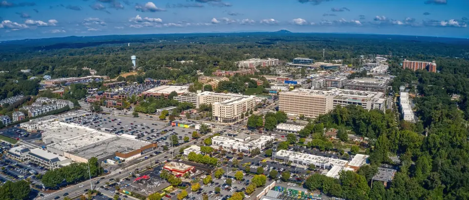 Sandy Springs, Georgia from the air: mid-rise buildings, shops and car parks set in dense tree cover that runs to the horizon